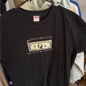 Supreme Black Tee with Pale Yellow Dollar 'Merry Christmas' Graphic